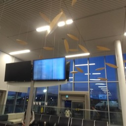A photo from an airport gate. The focus is on a single television, whose signal is extremely garbaled. You can just make out the text, "More oceans." In the background, the airstrip is visible at night through windows.